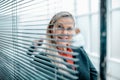 Successful business woman looking through window blinds. Royalty Free Stock Photo