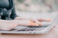 Successful business woman with bright red manicure typing on laptop keyboard outdoors on beach with sea view. Close up Royalty Free Stock Photo