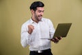 Successful businessman in black suit holding laptop. Fervent