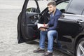 Successful businessman with documents in hand sits behind the wheel of a prestigious car Royalty Free Stock Photo