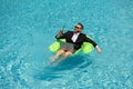 Successful businessman floating in suit in pool water. Summer vacations and travel concept. Funny business man drink Royalty Free Stock Photo