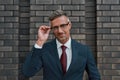 Successful businessman. Handsome mature man in classic suit adjusting his eyeglasses and looking at camera with smile Royalty Free Stock Photo