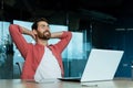 Successful businessman in office in a red shirt rests with his hands folded head with closed eyes, mature man with a Royalty Free Stock Photo