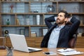 Successful businessman in office rests with his hands folded head with closed eyes, mature man with a beard works with a Royalty Free Stock Photo