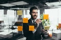 Successful businessman rewrites a task on a glass board with colored stickers, from phone and tablet Royalty Free Stock Photo
