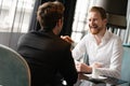 Successful businessman smiling while discussing with partner during meeting at coffee break Royalty Free Stock Photo