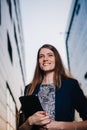 Successful businessman smiling, standing on the background of buildings and holding a tablet computer. City business woman working Royalty Free Stock Photo