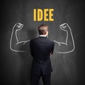 Successful businessman standing in front of a blackboard with the word `IDEA` Royalty Free Stock Photo