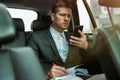 Successful businessman takes notes to planner from his smartphone while riding on back seat of car on way to meetting with Royalty Free Stock Photo