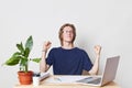 Successful businessman at work place clenches fists, celebrates his victory and triumph, being glad to sign contract with partners Royalty Free Stock Photo