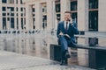 Successful businessman talking on mobile phone while working outside, sitting on bench Royalty Free Stock Photo