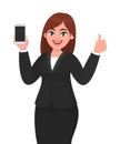 Successful businesswoman showing blank screen mobile, cell or smart phone and gesturing or making thumbs up sign with hand fingers