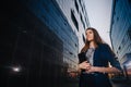 Successful businesswoman stands on the background of buildings and holding tablet computer. City business woman working. Royalty Free Stock Photo