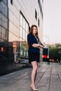 Successful businesswoman stands on the background of buildings and holding tablet computer. City business woman working. Royalty Free Stock Photo