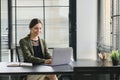 Successful businesswoman in a stylish dress is sitting at a desk in a modern office, using a laptop computer. She Royalty Free Stock Photo