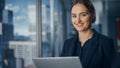Successful Businesswoman in Stylish Dress Working on Laptop, Standing Next to Window in Big City Royalty Free Stock Photo