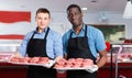 Successful sellers of butcher store offering fresh raw meat steak cutlets Royalty Free Stock Photo