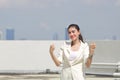 Successful cheerful young Asian businesswoman raising hands outside office. Thinking and thoughtful business concept Royalty Free Stock Photo