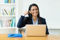 Successful cheering hispanic mature businesswoman at computer