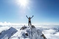 successful climber with arms raised standing on top of a snowy mountain Royalty Free Stock Photo