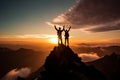 Successful climbers with raised hands standing on top of a mountain at sunset Royalty Free Stock Photo