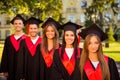 Successful confident five graduates in robes and hats with tassel smiling