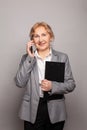 Successful confident friendly smart businesswoman uses her mobile phone, smiling and looking at camera