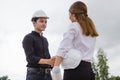 Successful deal, Female architect shaking hands with client in construction site after confirm blueprint for renovate building Royalty Free Stock Photo