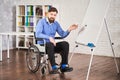 Successful disabled businessman teaching his team and drawing charts on a board