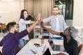 Successful diverse business team is giving high five and smiling while standing in office Royalty Free Stock Photo