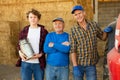 Successful elderly dairy farm owner with adult son and teen grandson standing in hayloft