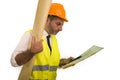 Successful engineer in hardhat and vest - young efficient and attractive builder or contractor holding blueprints reading