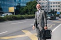 Successful entrepreneur with laptop bag waiting for taxi cab or a public bus in the city during sunny day Royalty Free Stock Photo