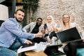 Successful excited multi-ethnic group of business people sitting together in office around the table with papers and Royalty Free Stock Photo