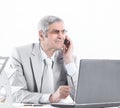 Experienced businessman with mobile phone sitting at his Desk