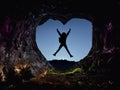 successful female mountaineer jumping at heart cave summit