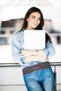 Successful female office worker with laptop is standing in skyscraper interior against big window with city view on background. Royalty Free Stock Photo