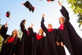 Successful five students with congratulations together throwing graduation hats in the air and celebrating