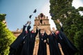 Successful five students with congratulations together throwing graduation hats in the air and celebrating at University