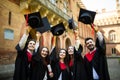 Successful five students with congratulations together throwing graduation hats in the air and celebrating