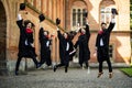 Successful five students with congratulations together throwing graduation hats in the air and celebrating
