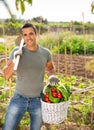 Successful gardener with basket of vegetables in garden