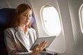 Successful asian businesswoman using a tablet to read a business article during a flight Royalty Free Stock Photo