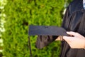 Successful graduate, in academic dresses, holding a graduation c
