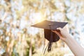 Successful graduate, in academic dresses, raised up graduation c