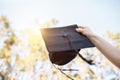 Successful graduate, in academic dresses, raised up graduation c