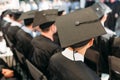 Successful graduates in academic dresses, at graduation, sitting Royalty Free Stock Photo