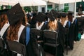 Successful graduates in academic dresses, at graduation, sitting Royalty Free Stock Photo