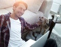 Successful guy stroking his pet sitting on the floor near the sofa Royalty Free Stock Photo