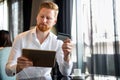 Successful handsome business man holding credit card, using digital tablet. Online shopping concept Royalty Free Stock Photo